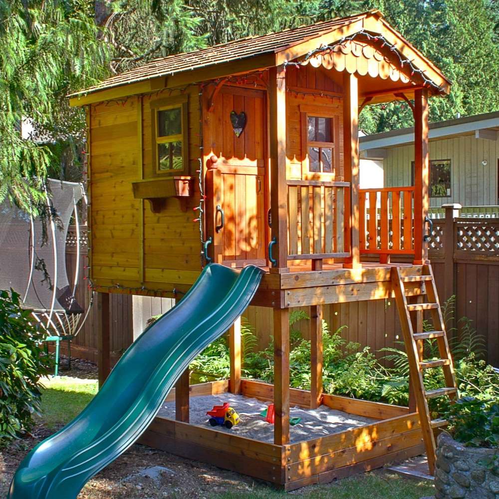 Outdoor Living Today 6x9 Sunflower Playhouse & Sandbox includes a raised playhouse design with a porch, ladder, slide, and built-in sandbox below