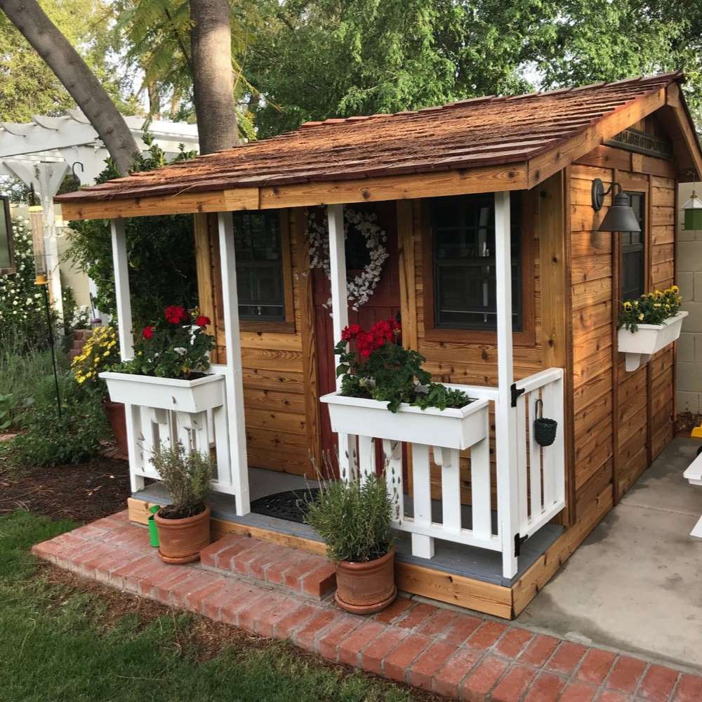 Outdoor Living Today 7x9 Cozy Cabin Signature Cedar Playhouse & Sandbox with ground-level porch, white trim, flower boxes, and classic cedar finish