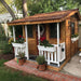 Outdoor Living Today 7x9 Cozy Cabin Signature Cedar Playhouse & Sandbox with ground-level porch, white trim, flower boxes, and classic cedar finish