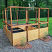 Outdoor Living Today 8×8 Raised Garden Bed stands in a wooded backyard, filled with soil and enclosed by wooden panels and wire mesh