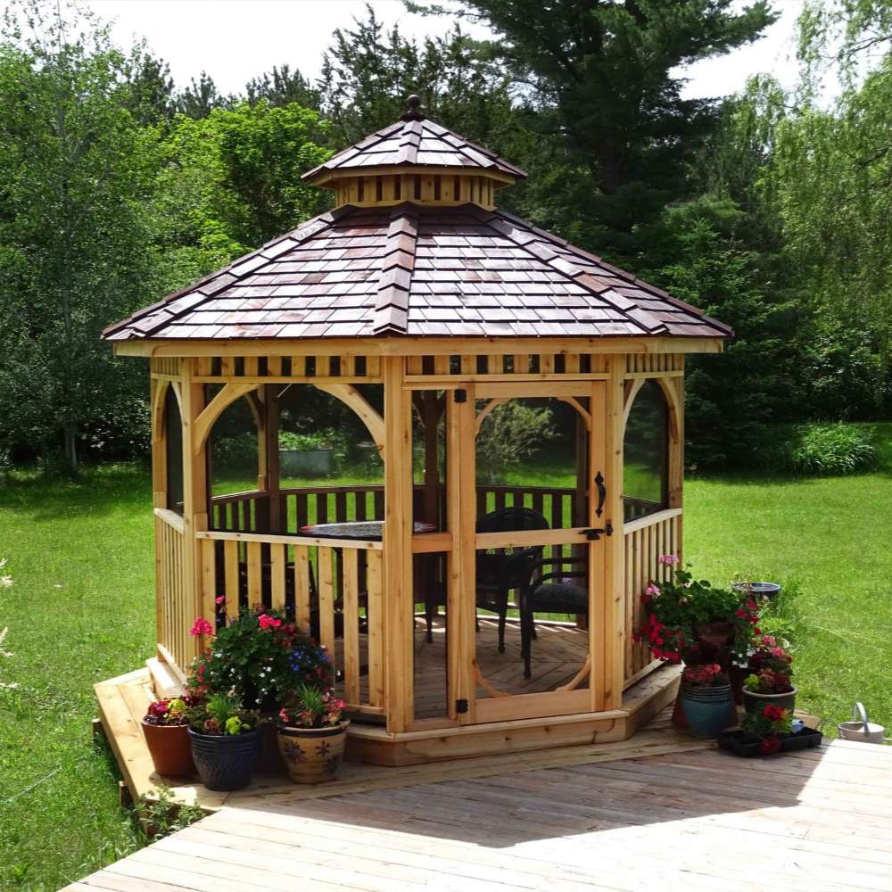 Outdoor Living Today Western Red Cedar Octagon Bayside Gazebo features screened windows and a door, set on a wooden deck in a grassy backyard