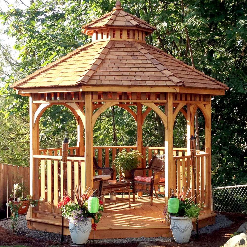 Outdoor Living Today Western Red Cedar Octagon Bayside Gazebo is styled with chairs and decor, creating a cozy outdoor seating area in a garden