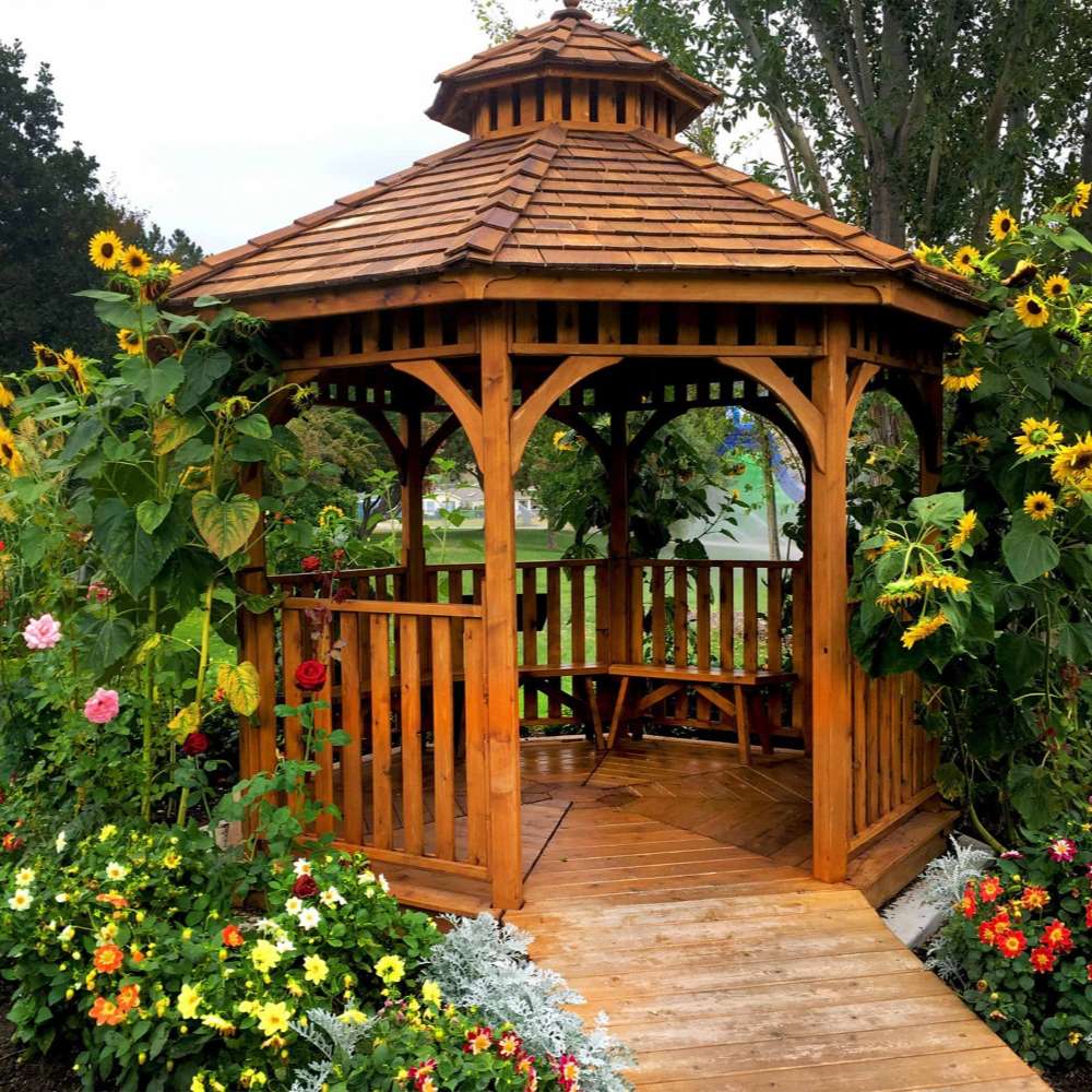 Outdoor Living Today Western Red Cedar Octagon Bayside Gazebo is surrounded by colorful flowers and greenery