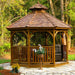 Outdoor Living Today Western Red Cedar Octagon Bayside Gazebo sits on a stone patio surrounded by trees