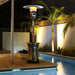 Outdoor Order Halo Traditional Heater glows at night on a pool deck lit by uplit palm trees