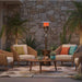 Outdoor Order Halo Traditional Heater stands between two wicker lounge chairs and a coffee table against a stone wall