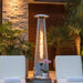 Outdoor Order PrismQuad Tower Heater glows beside a stacked stone wall between two white poolside loungers