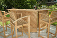 Outdoor patio scene features four stools and a bar table from Westminster Teak Somerset 5pc Teak High Bar Set with wine glasses and a bottle on top