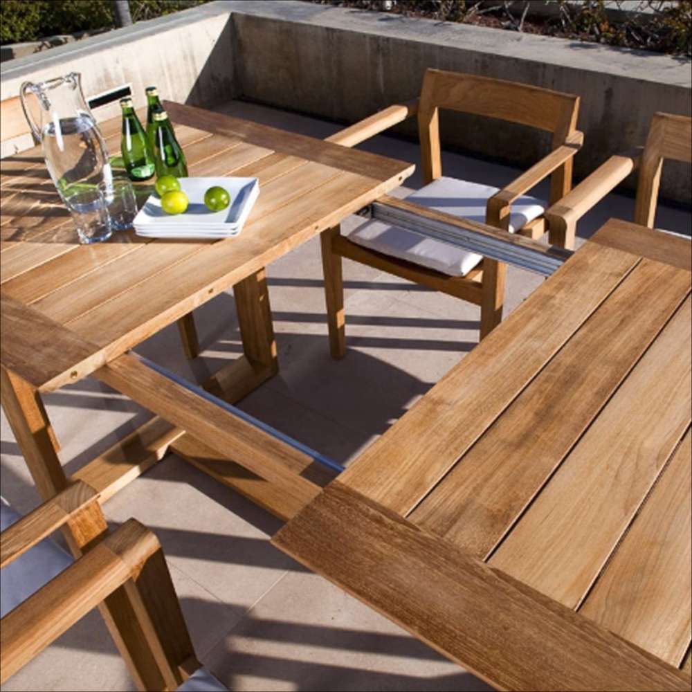 Outdoor patio scene shows the table partially extended with a visible leaf mechanism, topped with a pitcher, bottles, and limes, highlighting Westminster Teak Horizon Table & Bench Set