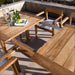 Outdoor patio scene shows the table partially extended with a visible leaf mechanism, topped with a pitcher, bottles, and limes, highlighting Westminster Teak Horizon Table & Bench Set