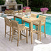Outdoor setup of Westminster Teak 5ft Laguna Teak Bar Table with matching stools beside a pool and patio seating