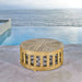 Outdoor view of Westminster Teak 36-Inch Kafelonia Teak Coffee Table on a patio by a pool with an ocean backdrop