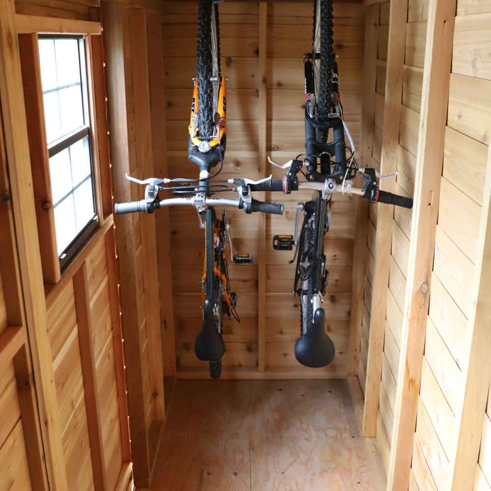 Outdoor Living Today 12×4 with Sliding Doors SpaceSaver Storage Shed neatly holds two bicycles hanging vertically inside its narrow wooden interior
