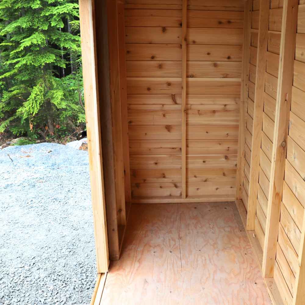 Outdoor Living Today 12×4 with Sliding Doors SpaceSaver Storage Shed shows a clean, empty wooden interior with sunlight spilling in from the open door