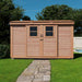 Outdoor Living Today 12×4 with Sliding Doors SpaceSaver Storage Shed stands at the end of a stone pathway in a grassy yard, with its twin windows and doors centered