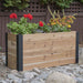 Outdoor Living Today 4×1.5 Urban Raised Garden Bed is shown in a rocky backyard filled with colorful blooming flowers
