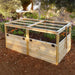 Outdoor Living Today 6×3 Raised Garden Bed sits in a flower-filled yard with mesh panels on top to shield plants while allowing airflow