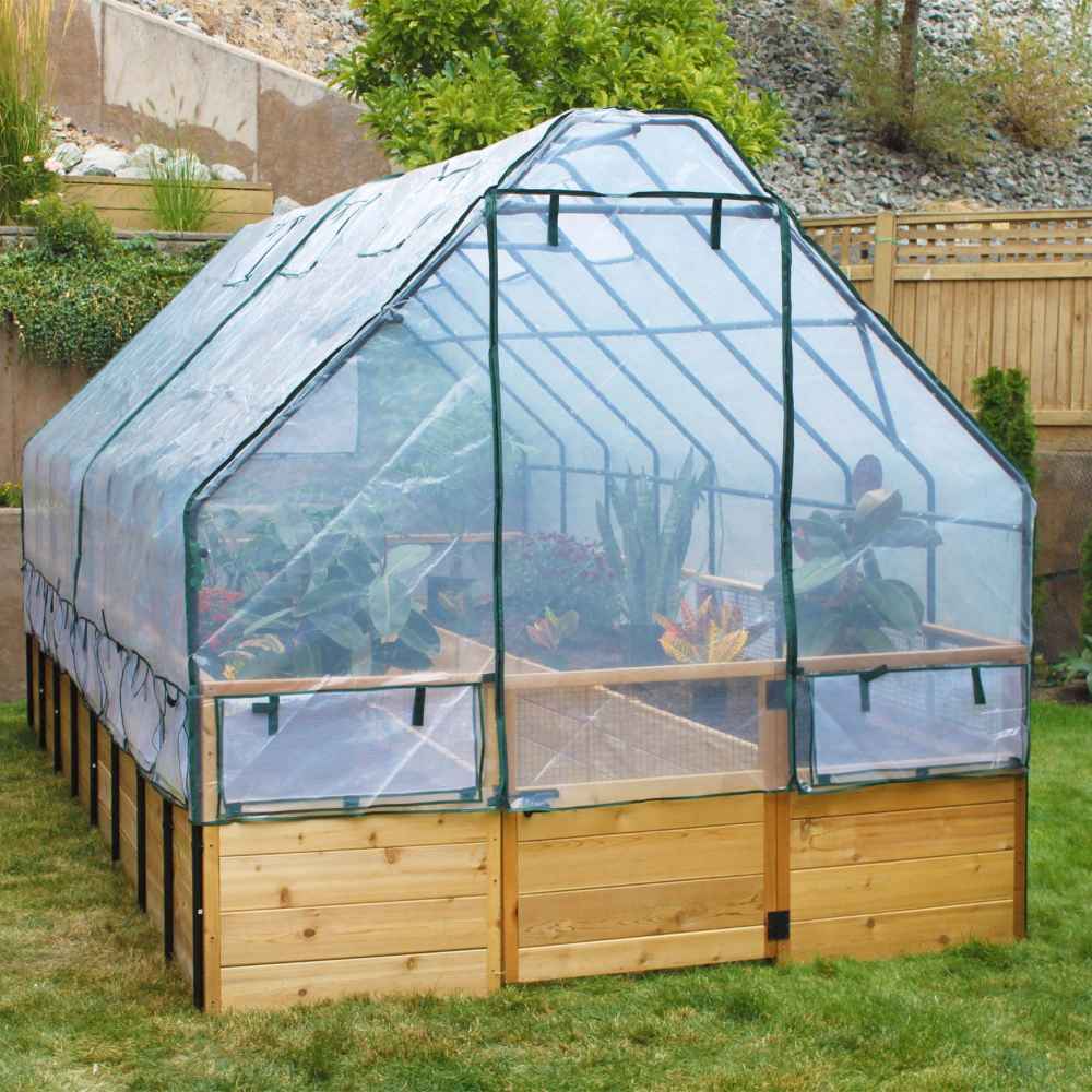 Outdoor Living Today 8×12 Raised Garden Bed is fully enclosed with a clear greenhouse cover, protecting vibrant plants inside on a grassy lawn
