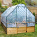Outdoor Living Today 8×12 Raised Garden Bed is fully enclosed with a clear greenhouse cover, protecting vibrant plants inside on a grassy lawn
