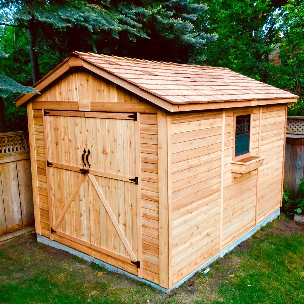Outdoor Living Today 8×12 Space Master Storage Shed is pictured with a side window and charming cedar shingle roof, sitting beautifully in a backyard