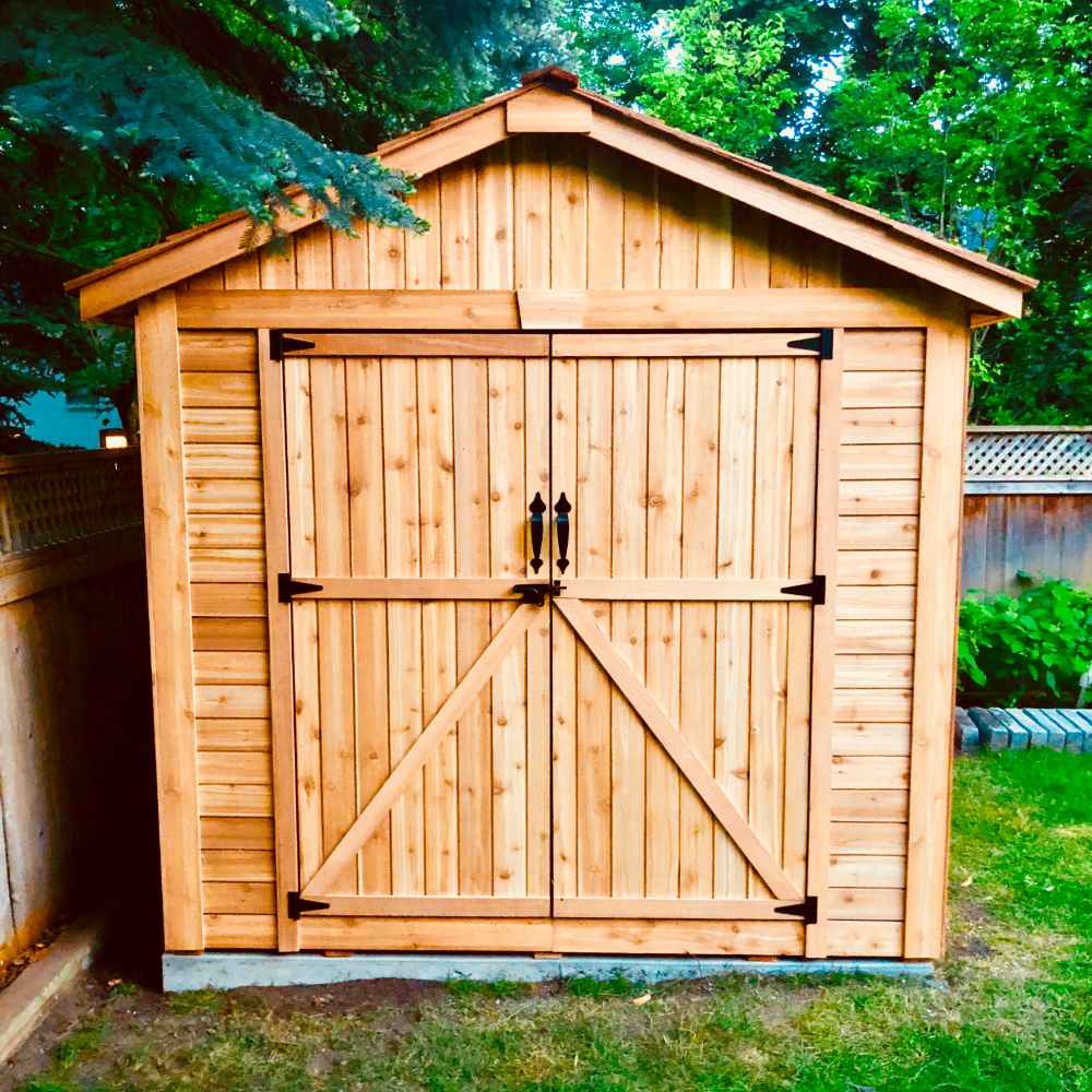 Outdoor Living Today 8×12 Space Master Storage Shed stands neatly on a lawn with closed double doors and simple wooden siding