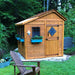 Outdoor Living Today 8×8 Sunshed Garden Shed sits in a wooded yard with blue flower boxes and a decorative design on the door