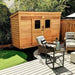 Outdoor Living Today GardenSaver 12×4 with Sliding Doors is placed next to a cozy patio with outdoor chairs and a table