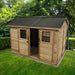 Outdoor Living Today Large 12×8 Cabana Garden Shed features a dark metal roof, sliding door, two windows, and an open door surrounded by lush greenery