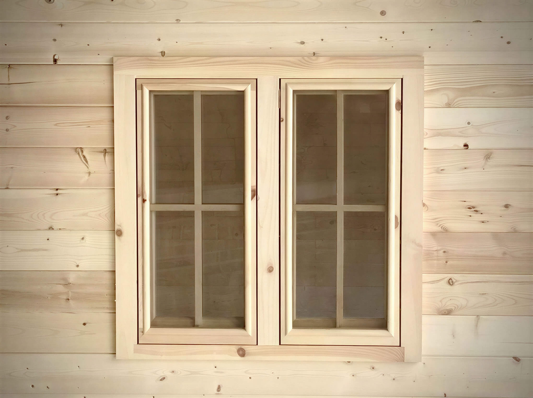 Pair of rectangular wooden windows with grid-pane glass panels on the exterior of the Sawmill Structures Harvest Grand Bungalow 107 Garden Room