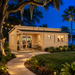 Pamplona 70 glowing brightly at night as family and friends watch sports inside, surrounded by illuminated tropical landscaping beside a Central Florida lake.