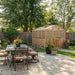 Patio dining area beside the 8x8 Outdoor Living Today Western Red Cedar Greenhouse Kit highlights a cozy outdoor setup