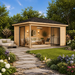 Pavilion ALU 44C Freedom Room fully furnished with cushioned seating, decorative pillows, lighting, and tables, set in a landscaped backyard garden with green grass, flowers, trees, and bright daytime surroundings.