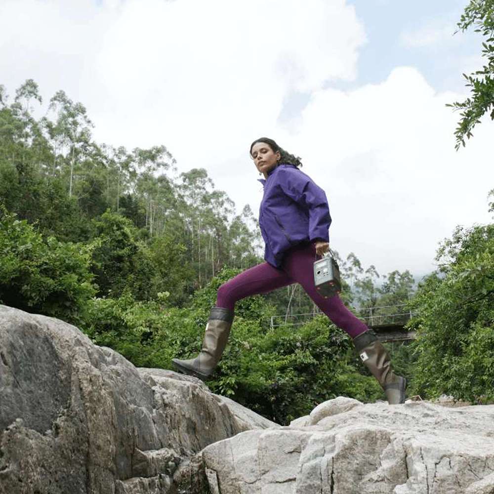 Person carries Jackery Explorer 300D Portable Power Station while walking across large rocks outdoors