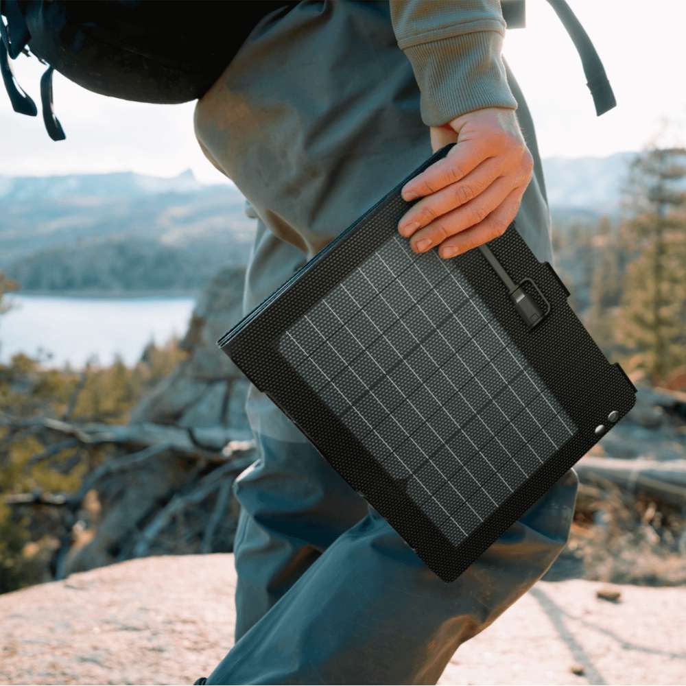 Person carries the folded Jackery SolarSaga 40 Air Solar Panel by hand on a hiking trail, showing its lightweight and portable design