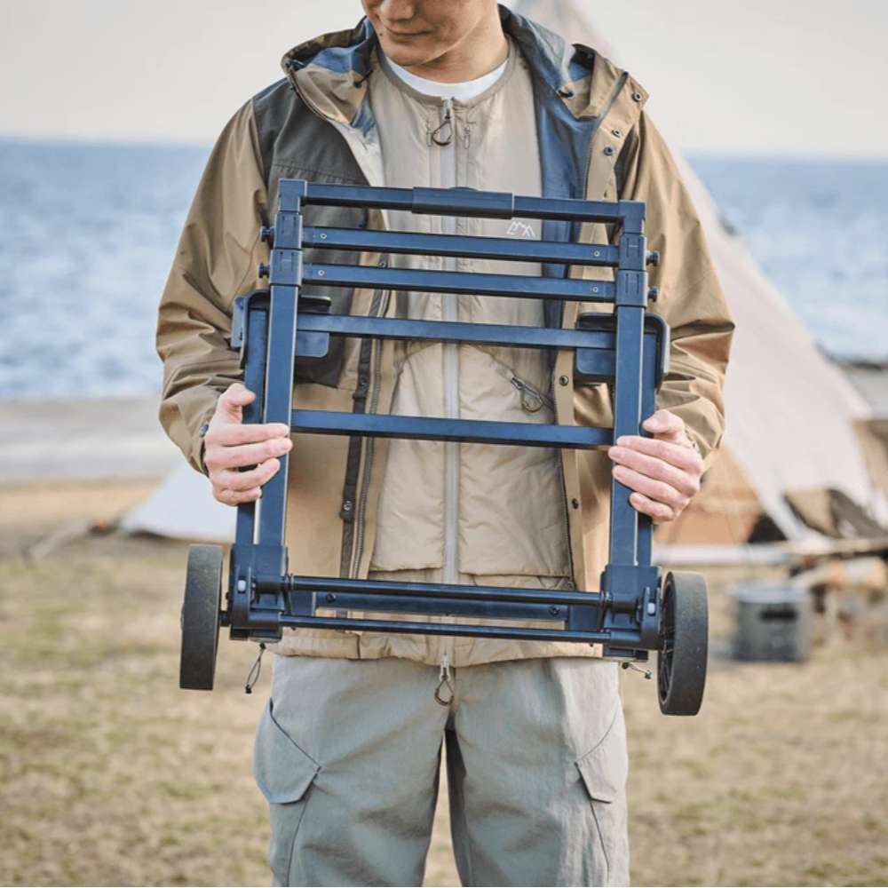 Person carrying the folded Jackery Power Station Trolley with one hand at a campsite beside a tent