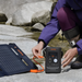 Person connects a foldable solar panel to Jackery Explorer 300D Portable Power Station beside a rocky stream