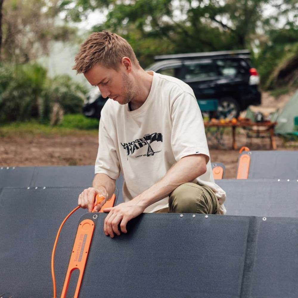 Person connects a folding solar panel using Jackery Solar Panel Connector at an outdoor campsite