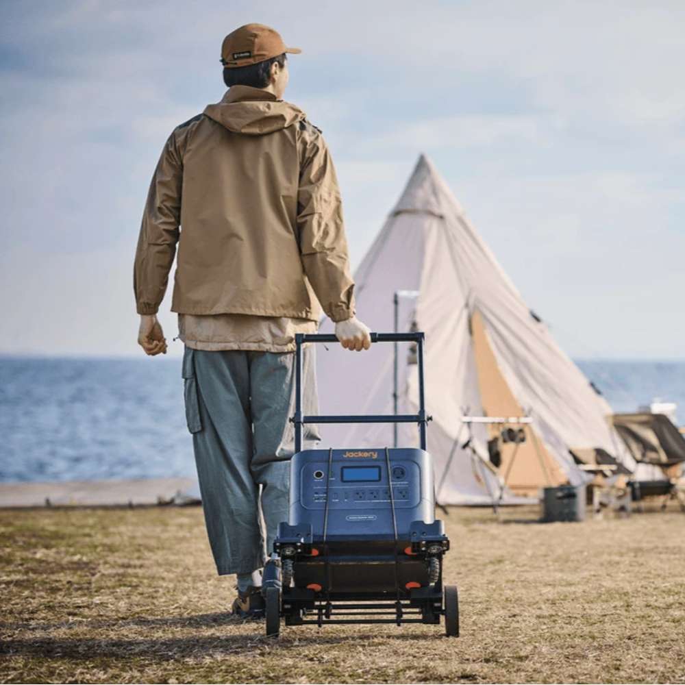 Person pulling a Jackery portable power station on the Jackery Power Station Trolley across a campsite toward a tent