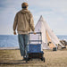 Person pulling a Jackery portable power station on the Jackery Power Station Trolley across a campsite toward a tent