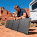 Person unfolds Jackery SolarSaga 100W Air Solar Panel beside an RV in a desert campsite