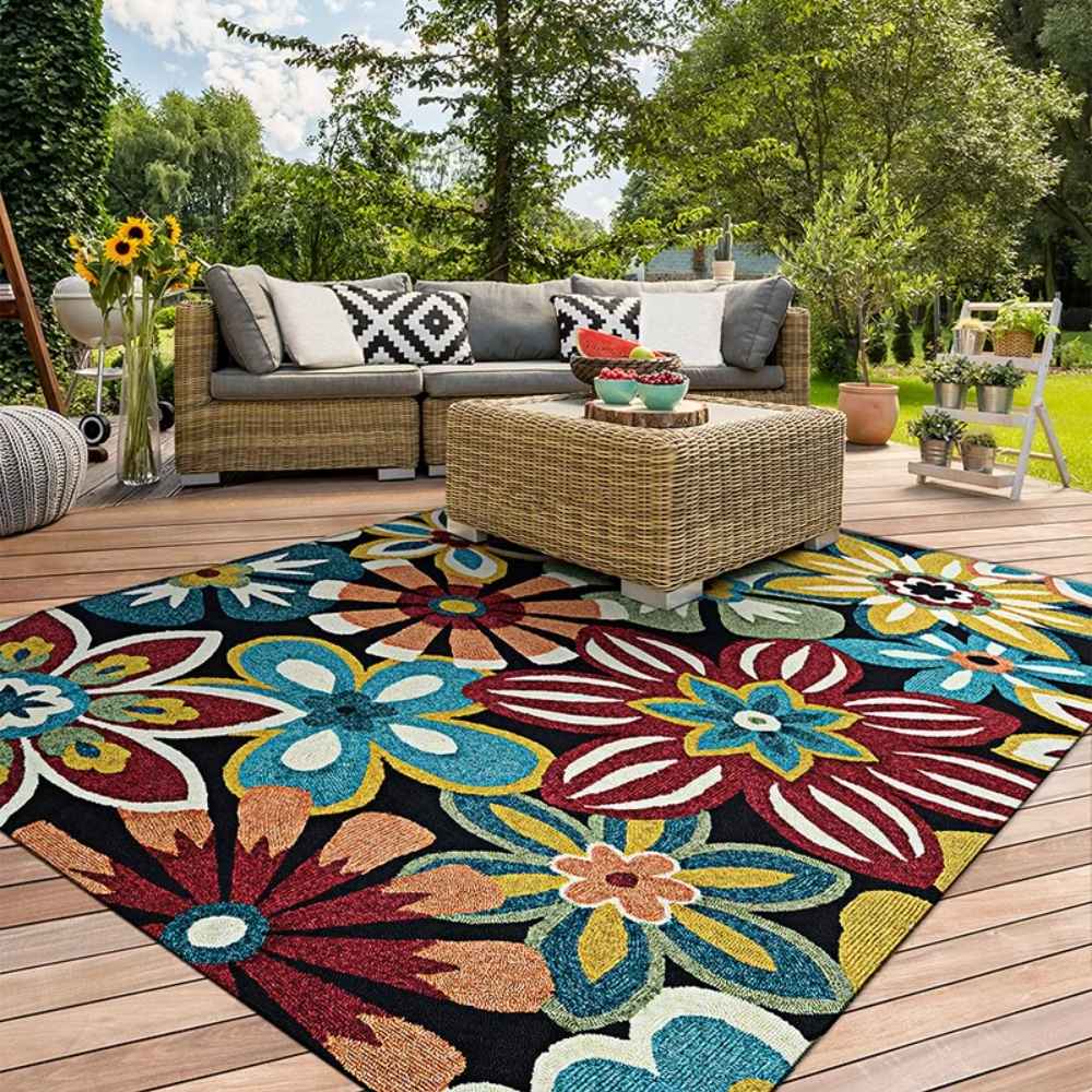 Placed on a wooden patio, the Couristan Covington Indoor/Outdoor Rug - Geranium/Navy-Multi brightens a cozy outdoor seating area with bold, cheerful flowers