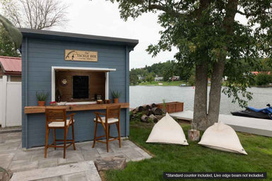 Positioned beside a lake, the Sawmill Structures The Lakeside Versa Cabana 67 Garden Room offers a charming outdoor bar experience with stools and soft bean bag chairs