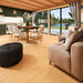 The interior of the GardenHouse24 USA Ramsay 70 A ALU Garden Room is warmly lit and elegantly furnished with a dining table, kitchen, and soft curtains framing scenic lake views
