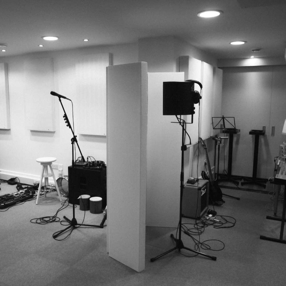 Recording studio setup featuring microphones, instruments, and multiple GIK Acoustics ScreenPanel Vocal Screen units creating acoustic separation