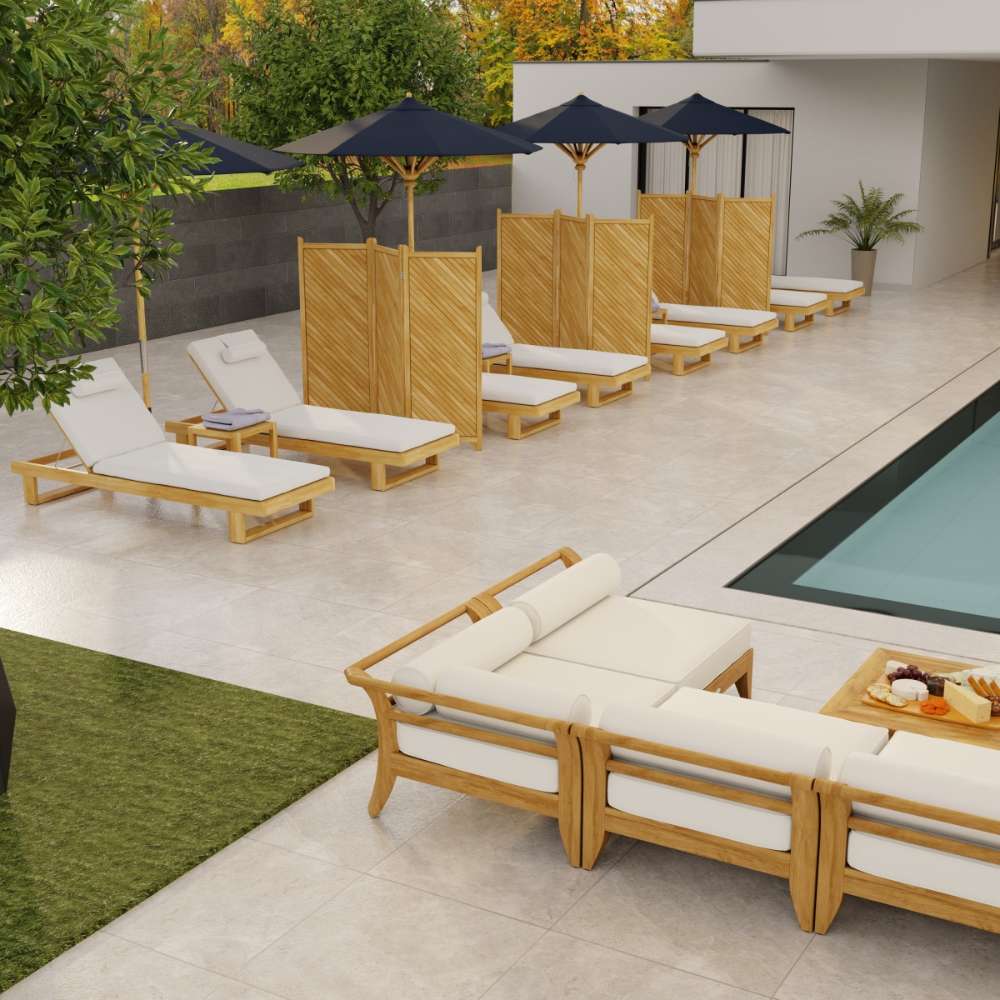 Row of Westminster Teak Horizon Chaise Lounger chairs with white cushions lines a modern poolside patio, shaded by dark umbrellas and separated by wooden privacy panels