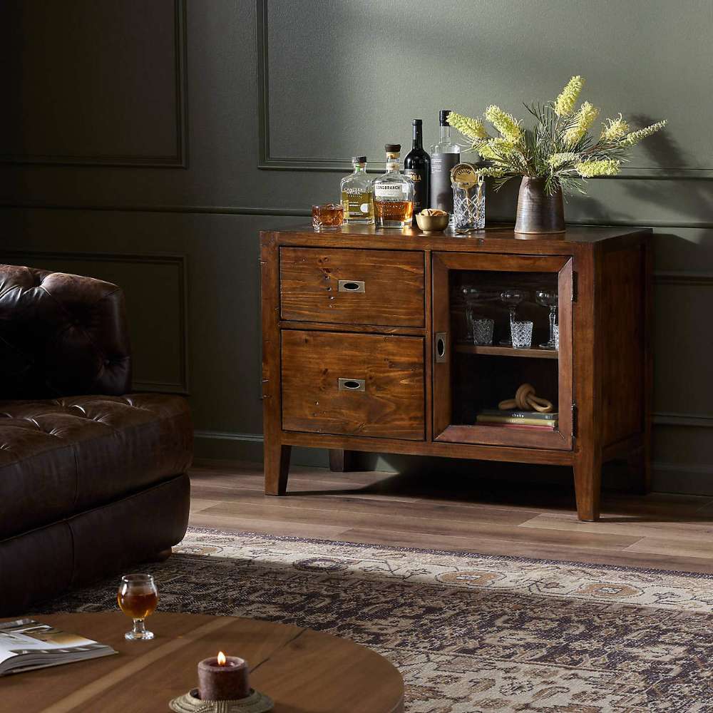 Rustic Crate & Barrel Morris Chocolate Brown Credenza styled as a home bar with storage for bottles, glassware, and décor