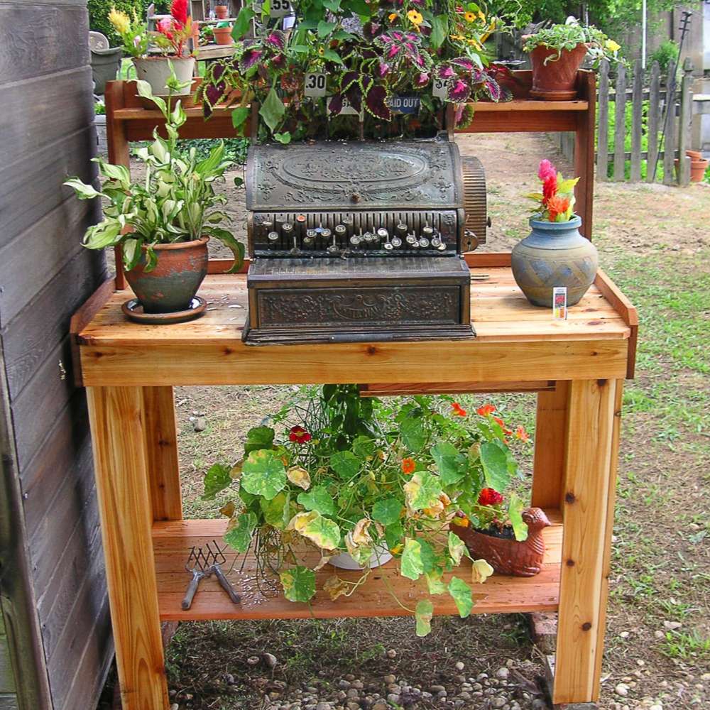 Rustic outdoor setup shows plants and decor on a bench, with Outdoor Living Today 4×2 Western Red Cedar Potting Bench at the center