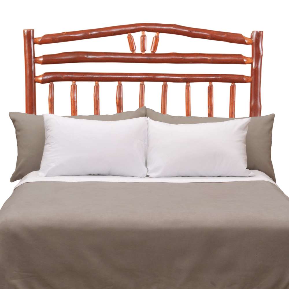 Rustic wooden bed with log-style rails and Fireside Lodge Hickory Log Wagon Wheel Headboard sits behind neatly arranged white and gray bedding