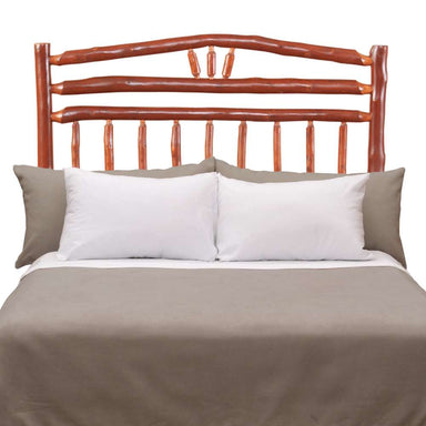 Rustic wooden bed with log-style rails and Fireside Lodge Hickory Log Wagon Wheel Headboard sits behind neatly arranged white and gray bedding
