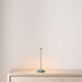 Sage Crate & Barrel Pina Pro Metal Table Lamp by Zafferano America glows warmly on a light wood console against a neutral wall
